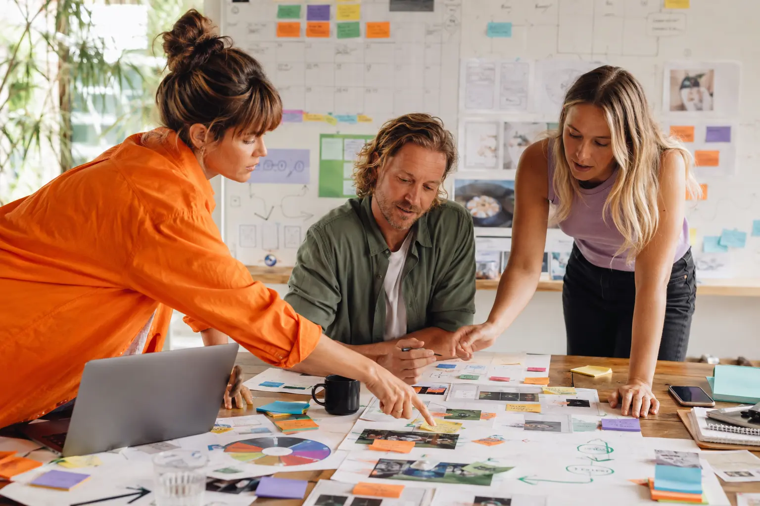 Three people mapping a business workflow together in a bright Remix studio, with handwritten notes, arrows and next steps spread across the table